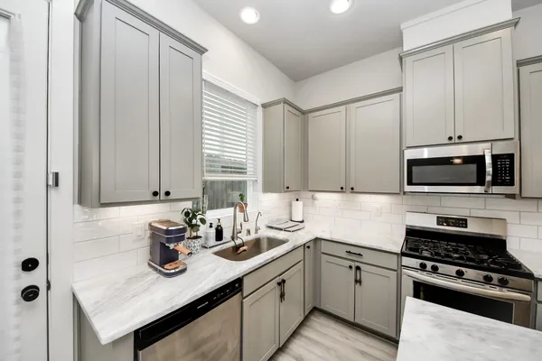 a kitchen with stainless steel appliances granite countertop a sink stove and cabinets