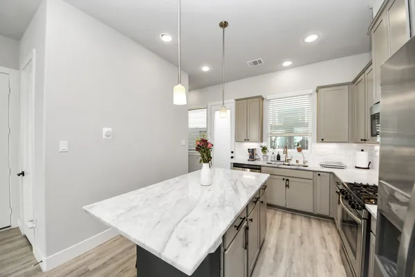 a large kitchen with lots of counter space a sink appliances and living room view