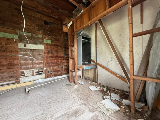 a view of an empty room with wooden floor and furniture