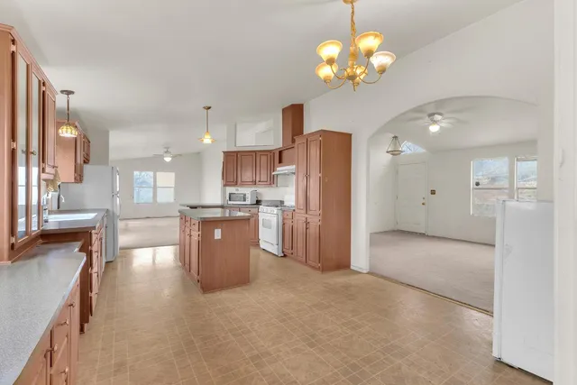 a kitchen with stainless steel appliances kitchen island granite countertop a refrigerator a sink dishwasher a dining table and chairs with wooden floor