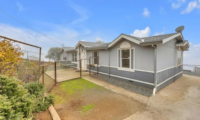 a view of a house with backyard and trees in the background