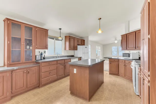 a large kitchen with kitchen island granite countertop a sink counter space stainless steel appliances and cabinets