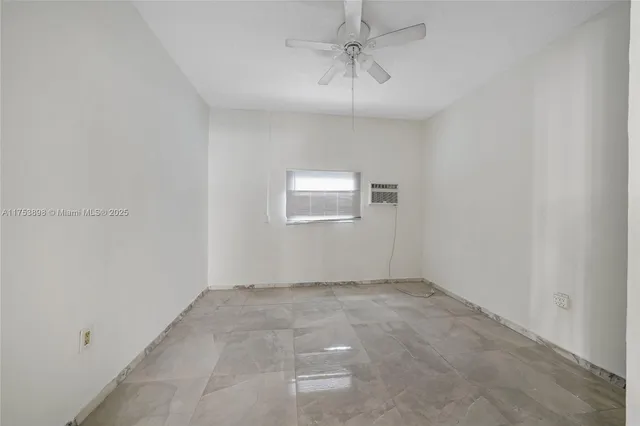 an empty room with a chandelier fan and windows
