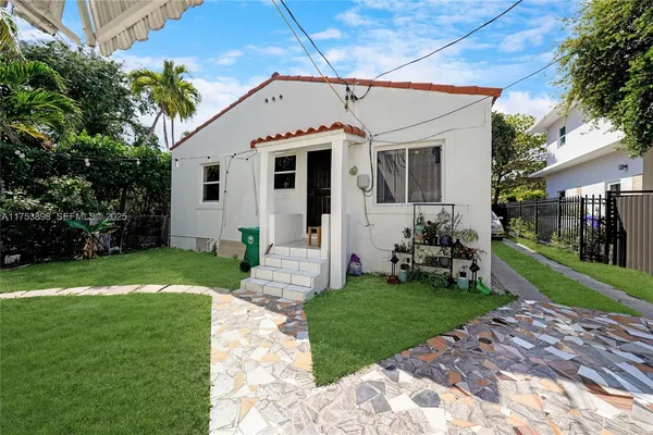 a view of a white house next to a yard with big trees
