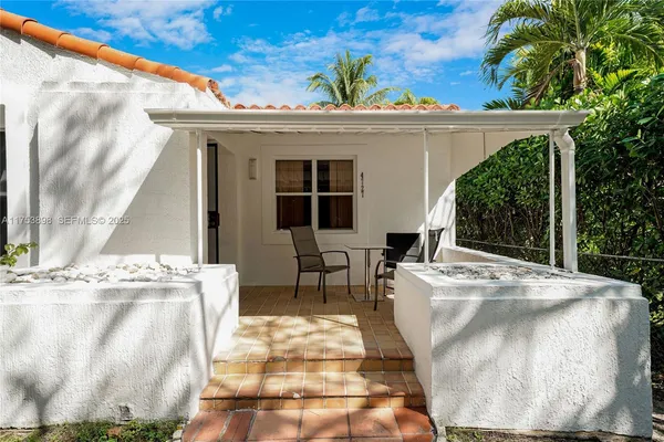 a view of a white house with table and chairs