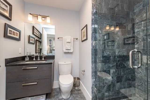 a bathroom with a granite countertop toilet a sink a mirror and shower