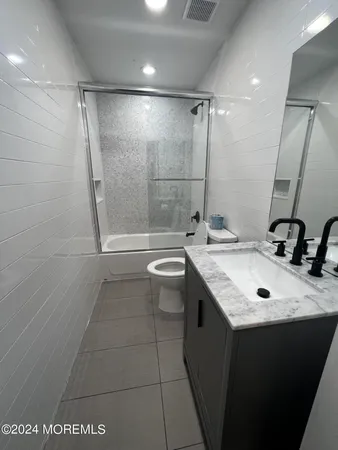 a bathroom with a granite countertop sink a toilet and shower
