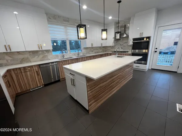 a large white kitchen with a large counter top kitchen appliances and a sink