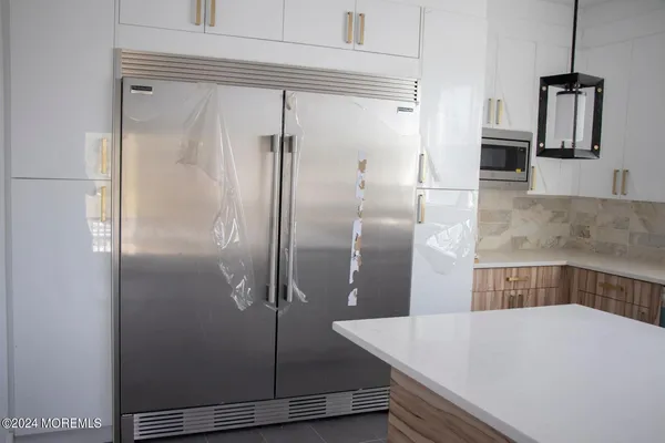 a view of a refrigerator in kitchen and an empty room