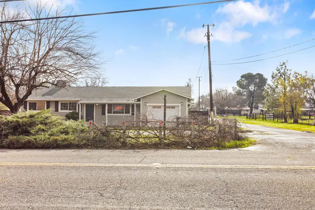 a front view of a house with a garden and lake view