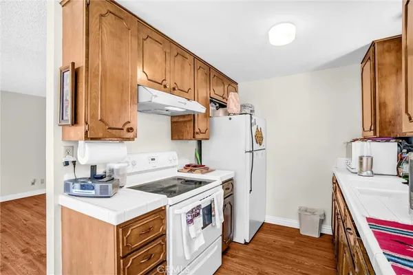 a kitchen with stainless steel appliances a stove a sink a refrigerator wooden floor and cabinets