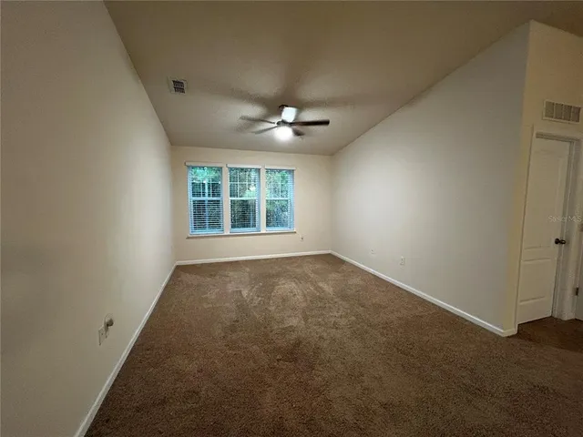an empty room with a window and a ceiling fan