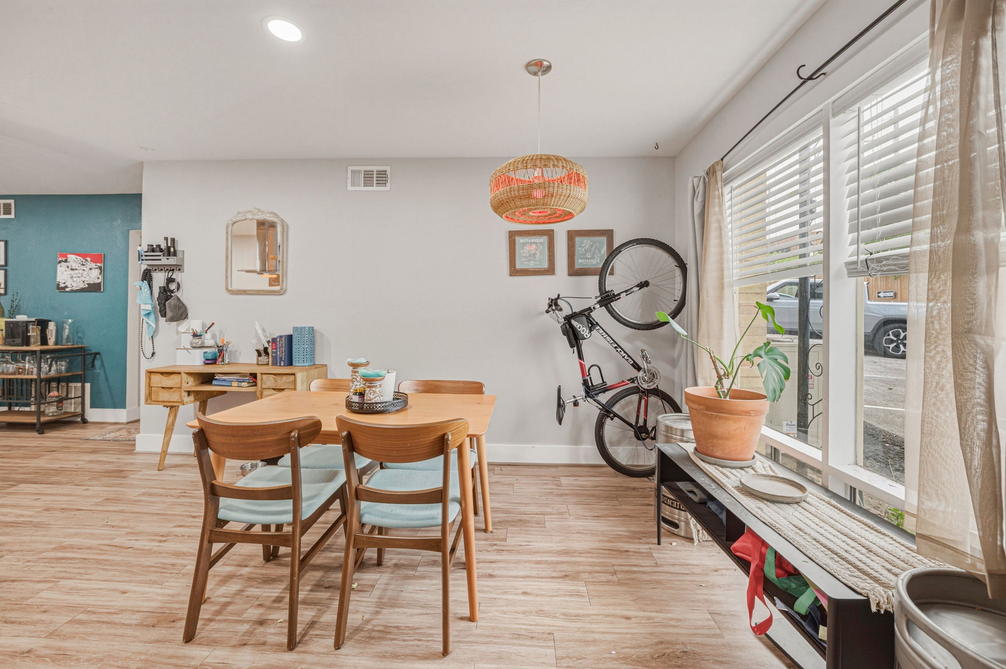 5332 Balcones Drive, Unit B Austin, TX 78731 - Photo 5 of 15 The property features wood-look flooring throughout, a dining area with a natural wood table and chairs, and large windows with blinds and curtains for privacy and light control