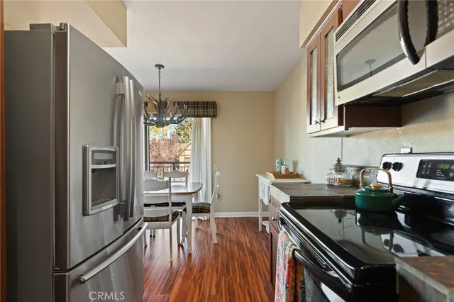 a kitchen with stainless steel appliances a stove a sink dishwasher a refrigerator with wooden floor and cabinets