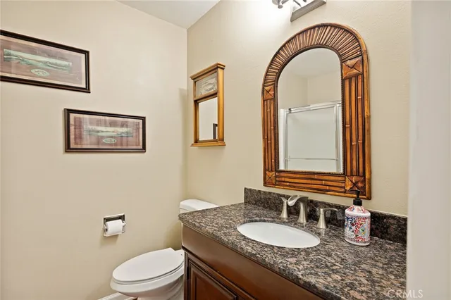 a bathroom with a granite countertop toilet a sink and a mirror
