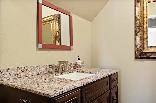 a bathroom with a granite countertop sink and a mirror