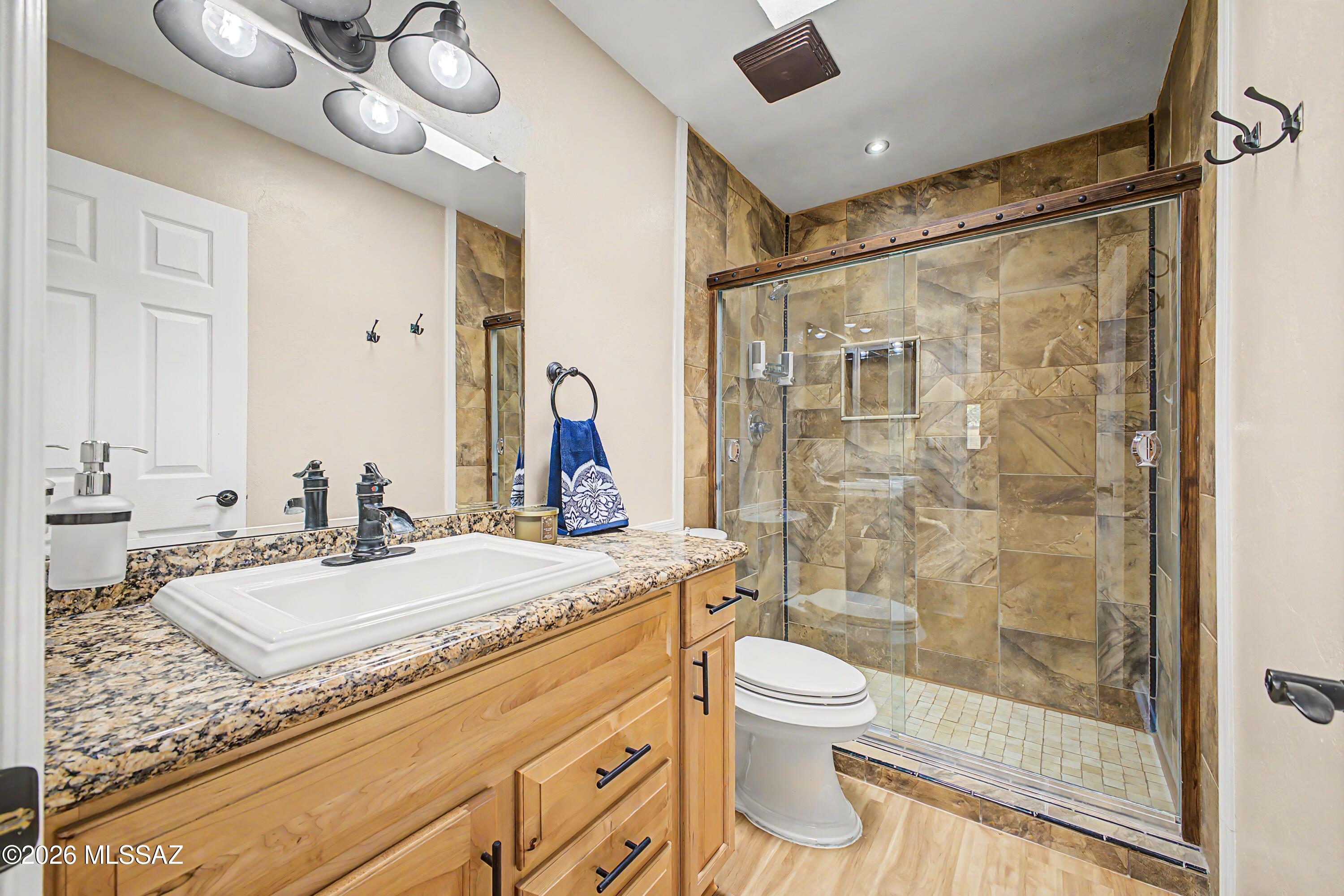 3781 East Edison Street Tucson, AZ 85716 - Photo 22 of 28 a bathroom with a granite countertop sink a toilet and shower