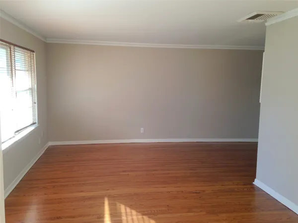 a view of an empty room with wooden floor and windows