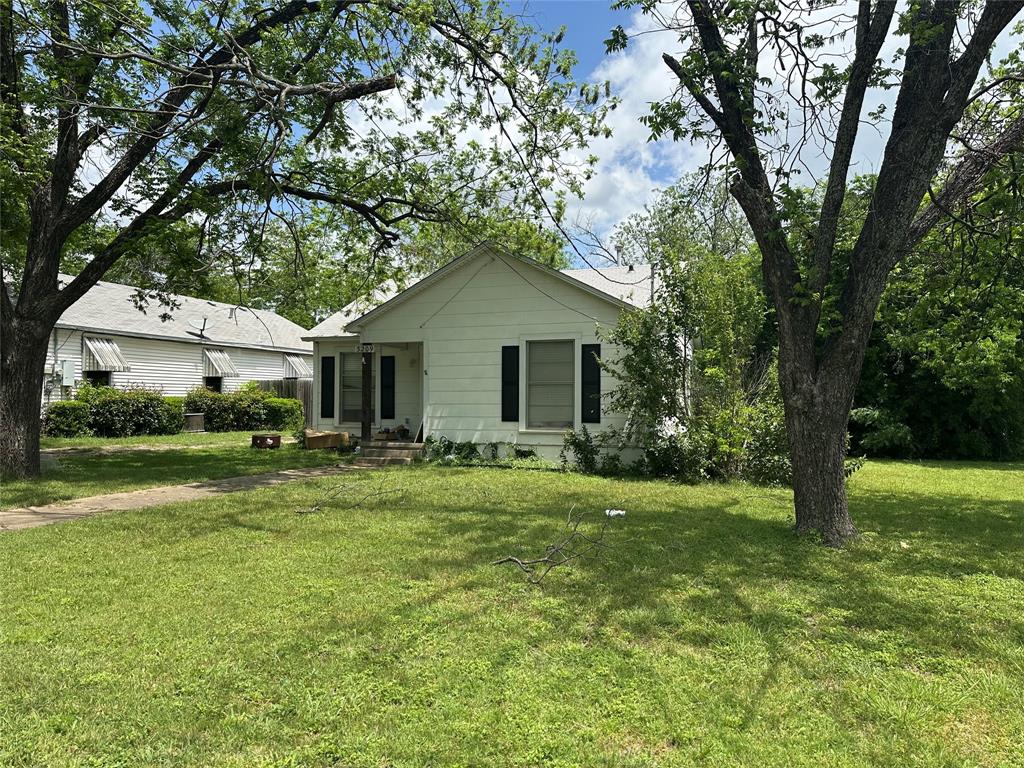 a front view of a house with a garden and trees