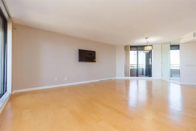 a view of an empty room with window and wooden floor