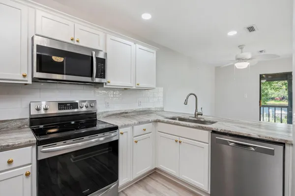 a kitchen with stainless steel appliances granite countertop a sink dishwasher a stove microwave and oven with white cabinets