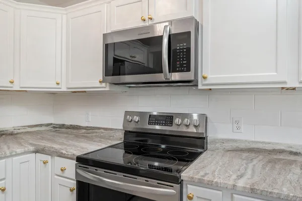 a kitchen with granite countertop a stove and a microwave