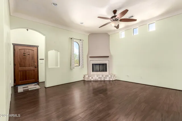 an empty room with wooden floor a ceiling fan and windows