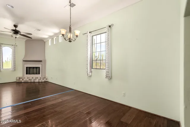 a view of an empty room with window and chandelier fan