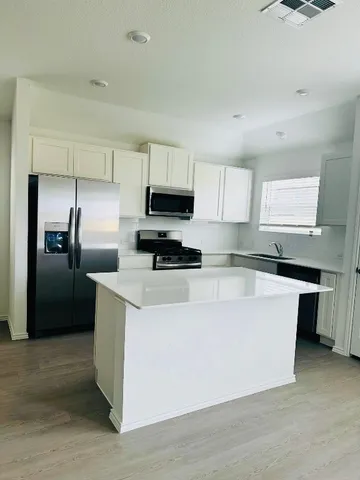 a kitchen with stainless steel appliances a refrigerator a sink a stove a microwave and cabinets