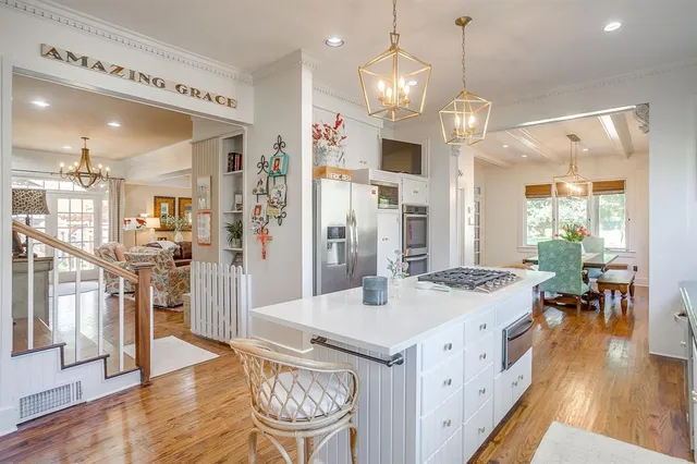 a open kitchen with stainless steel appliances granite countertop a sink dishwasher a refrigerator a dining table and chairs with wooden floor