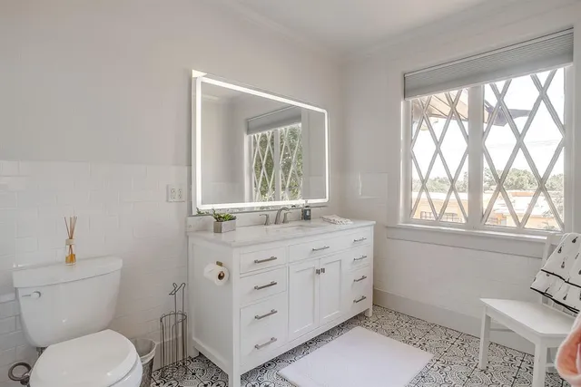 a bathroom with a granite countertop toilet a sink a large mirror and a window