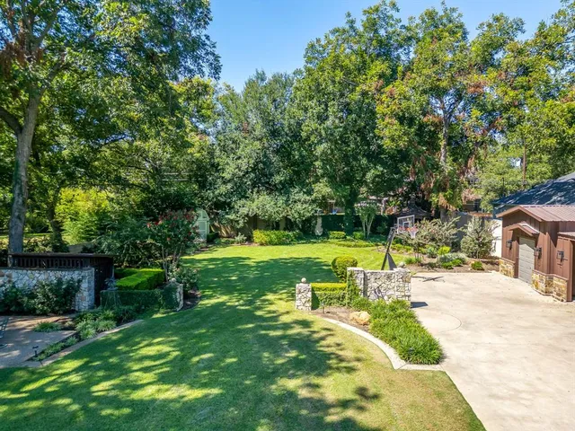 a view of a house with a big yard potted plants and large tree