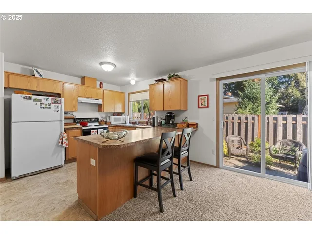 a kitchen with a refrigerator a stove a dining table and chairs