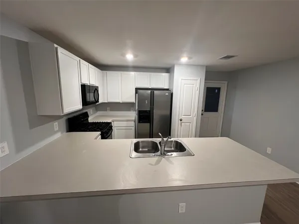 a kitchen with kitchen island a refrigerator sink and stove