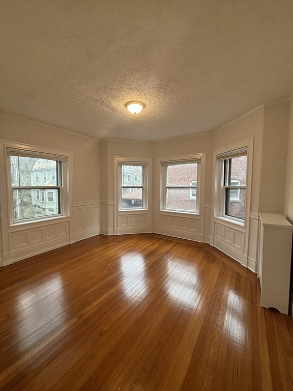 6 Beals Street, Unit 2 Brookline, MA 02446 - Photo 2 of 9 a view of an empty room with wooden floor and a window