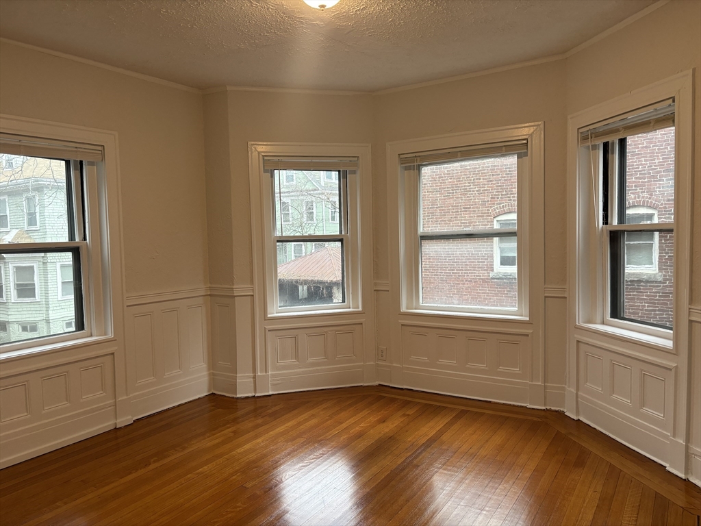 6 Beals Street, Unit 2 Brookline, MA 02446 - Photo 3 of 9 an empty room with wooden floor and windows