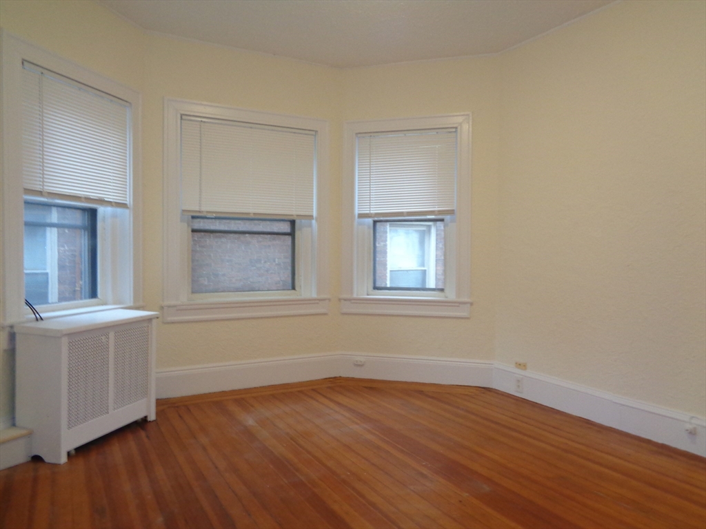 6 Beals Street, Unit 2 Brookline, MA 02446 - Photo 3 of 8 a view of an empty room with wooden floor and a window