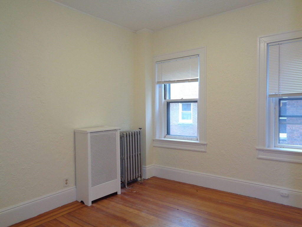 6 Beals Street, Unit 2 Brookline, MA 02446 - Photo 4 of 8 an empty room with wooden floor and windows