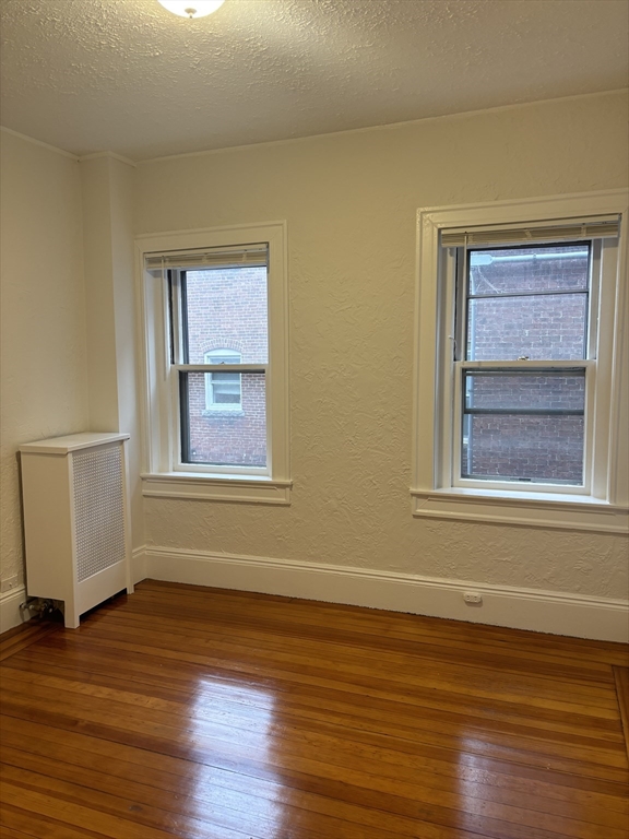 6 Beals Street, Unit 2 Brookline, MA 02446 - Photo 4 of 9 a view of an empty room with wooden floor and a window