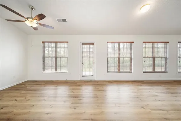 a view of an empty room with a window and wooden floor