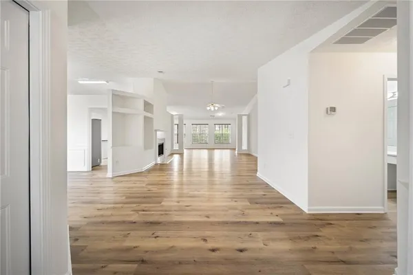 a view of an empty room with wooden floor and a bathroom