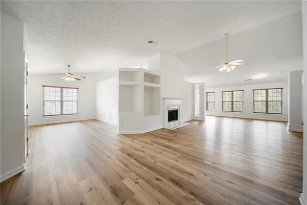 a view of an empty room with window and wooden floor