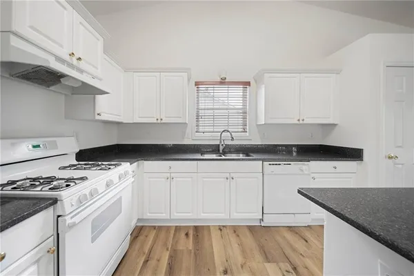 a kitchen with granite countertop a sink a stove and cabinets