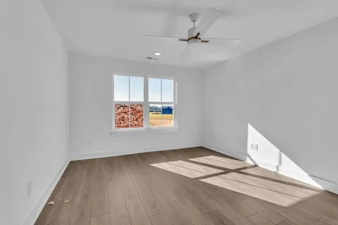 a view of an empty room with a window and wooden floor