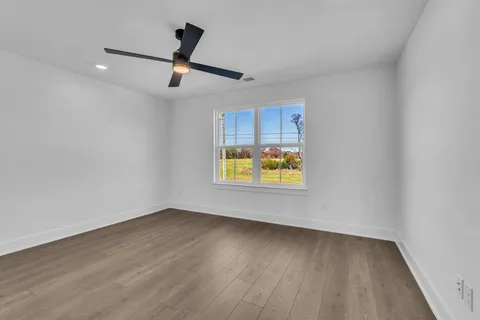 an empty room with wooden floor chandelier and windows