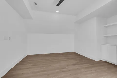 an empty room with wooden floor and ceiling fan