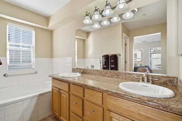 a bathroom with a granite countertop sink a large mirror and a bathtub