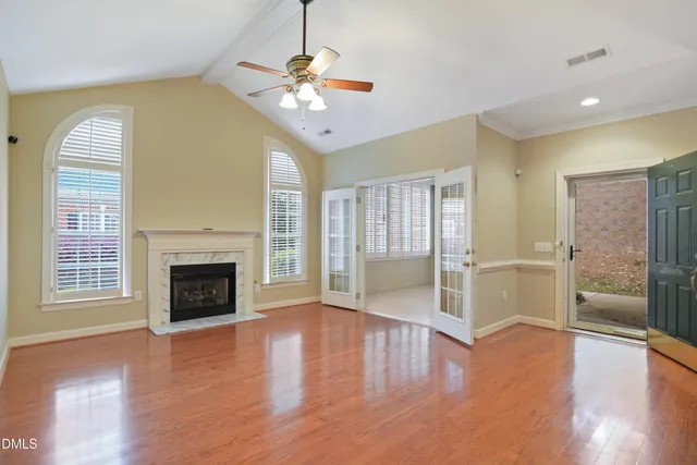 a view of an empty room with wooden floor fireplace and a window