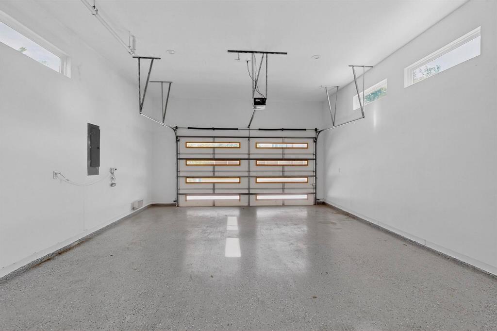 3946 North Cresthaven Road Dallas, TX 75209 - Photo 20 of 38 Spacious garage featuring a modern overhead door with frosted glass panels, durable epoxy flooring, crisp white walls, and high transom windows