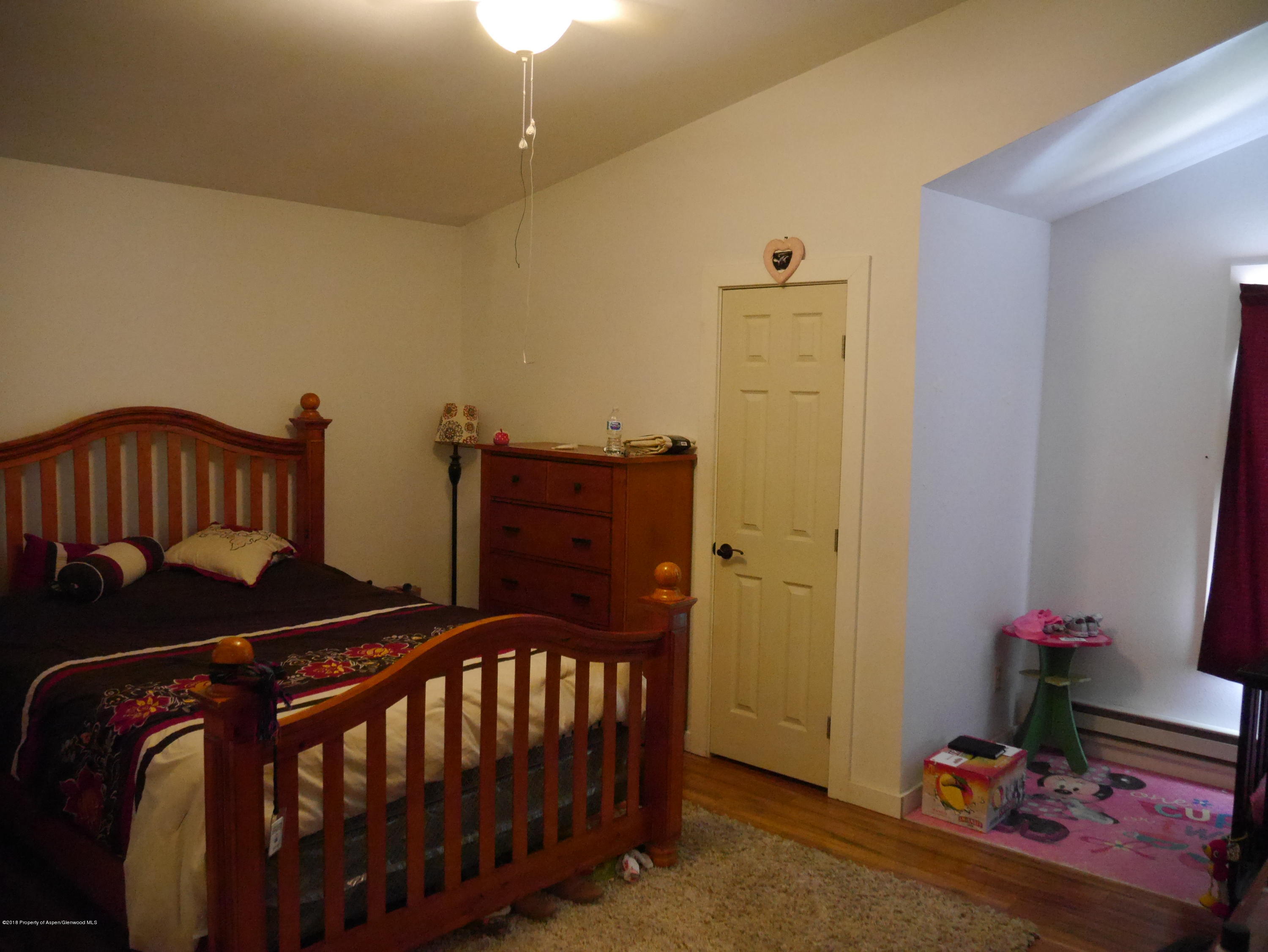 425 West 3rd Street Rifle, CO 81650 - Photo 8 of 14 a bedroom with a bed and wooden floor